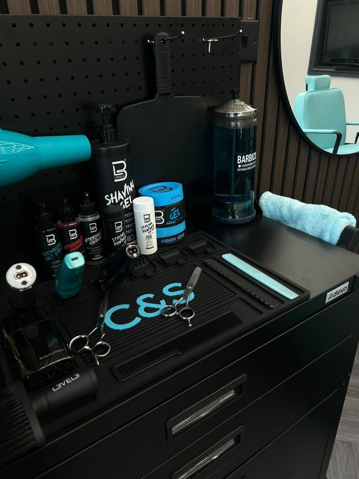 Clippers, scissors, shaving gel and styling products laid out on a black station at Image Barberz